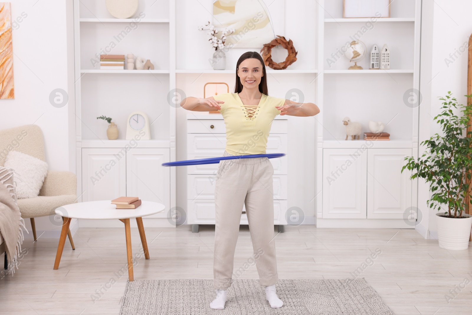 Photo of Smiling woman training with hula hoop at home