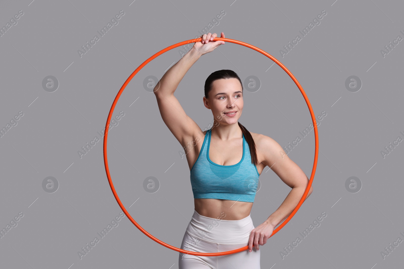 Photo of Smiling woman with hula hoop on grey background