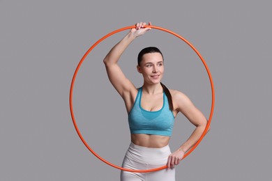 Photo of Smiling woman with hula hoop on grey background