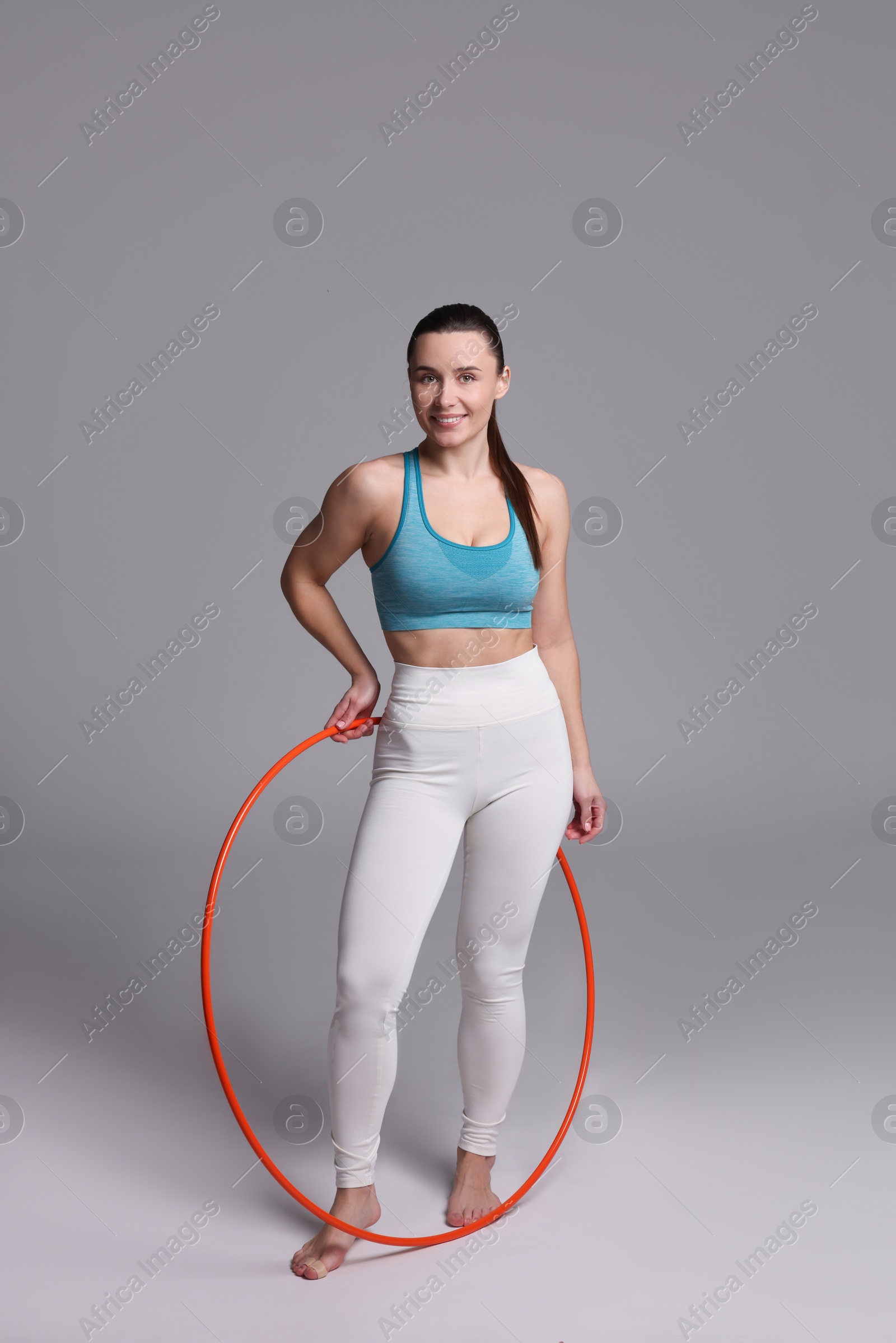 Photo of Smiling woman with hula hoop on grey background