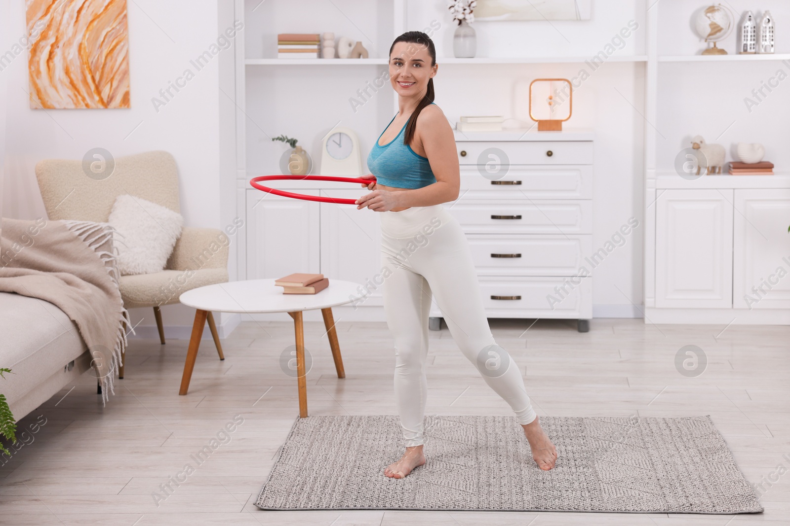 Photo of Smiling woman training with hula hoop at home