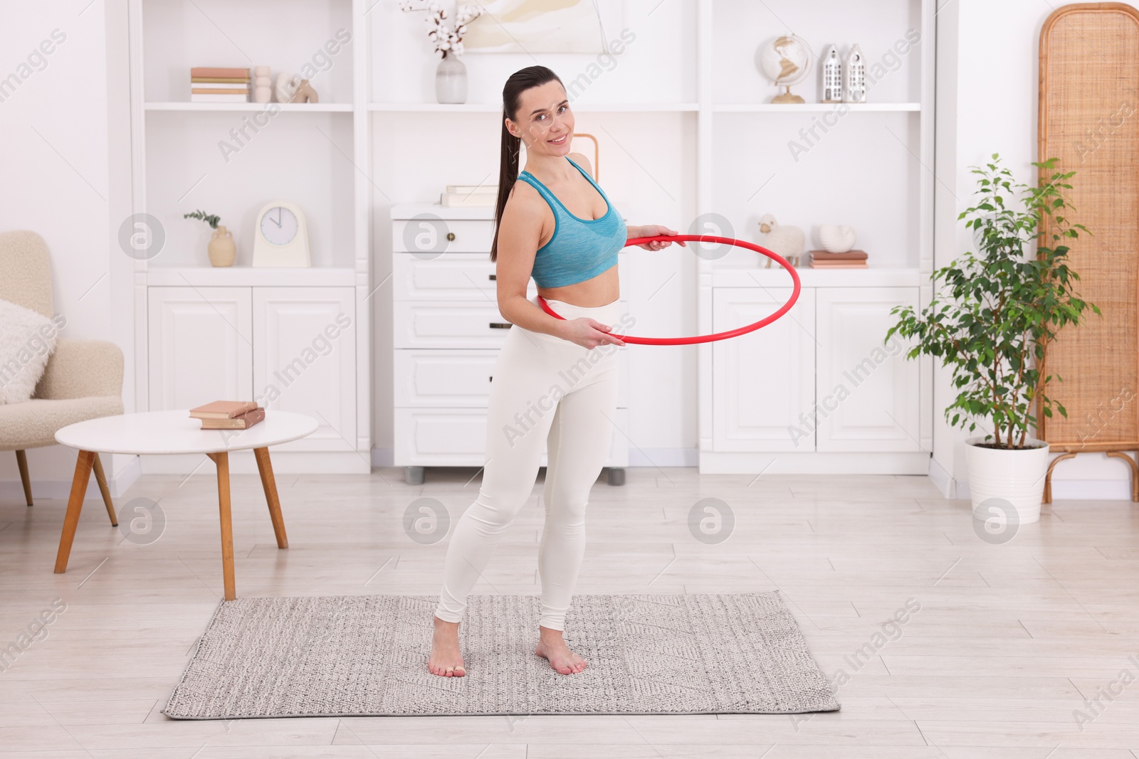 Photo of Smiling woman training with hula hoop at home