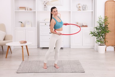 Photo of Smiling woman training with hula hoop at home