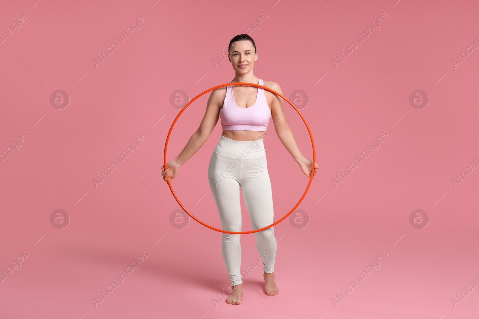 Photo of Smiling woman with hula hoop on pink background