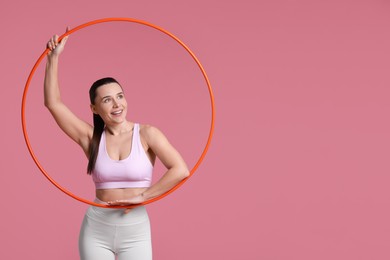 Photo of Smiling woman with hula hoop on pink background. Space for text