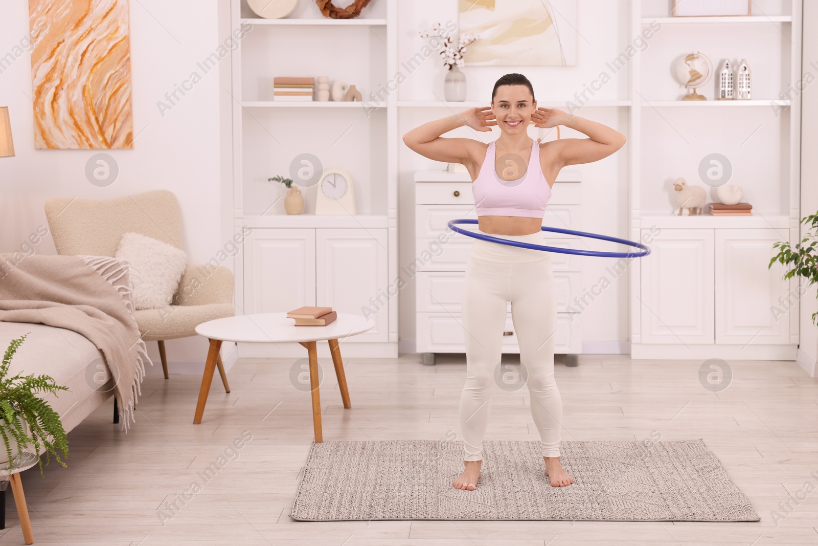 Photo of Smiling woman training with hula hoop at home