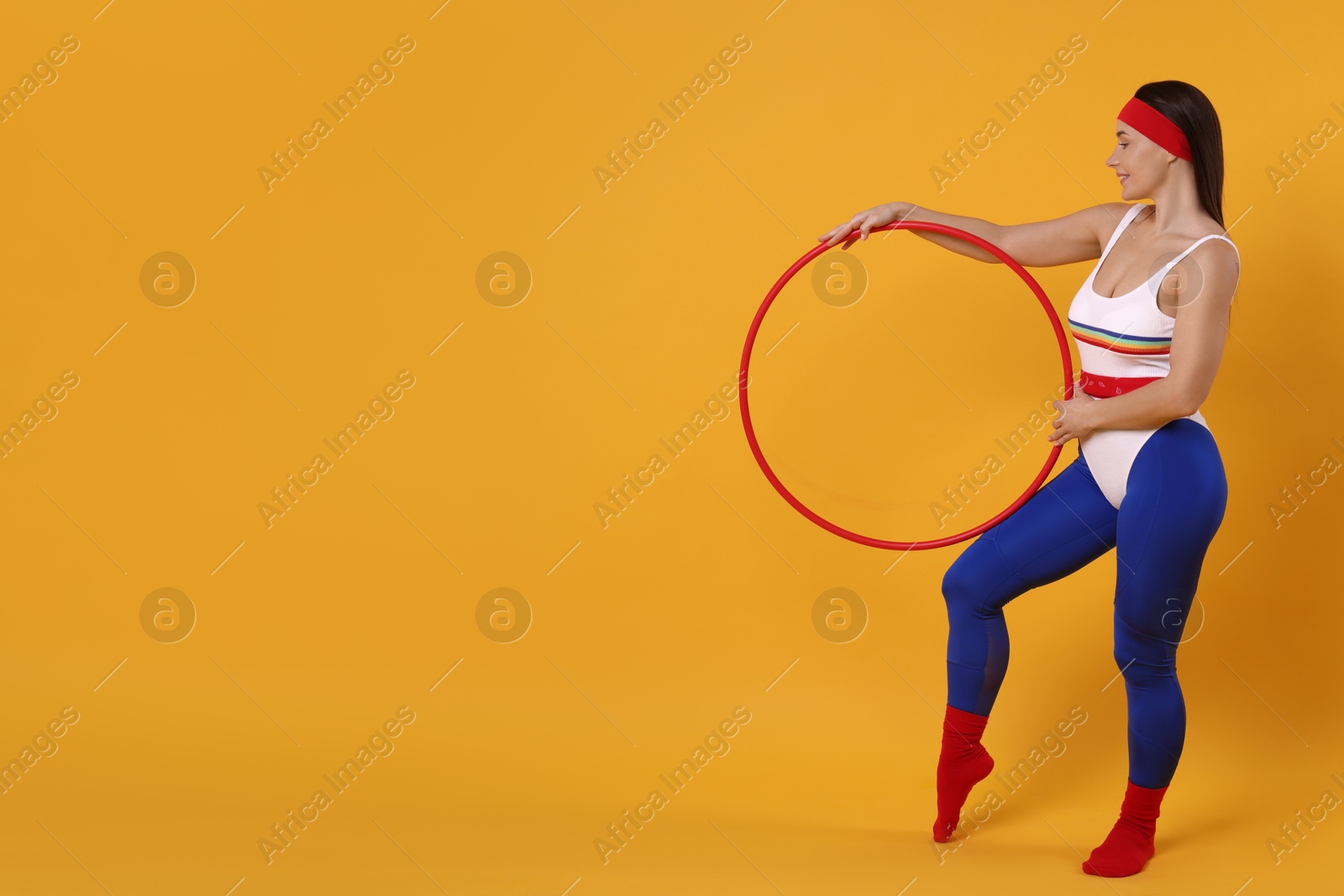 Photo of Smiling woman with hula hoop on orange background. Space for text