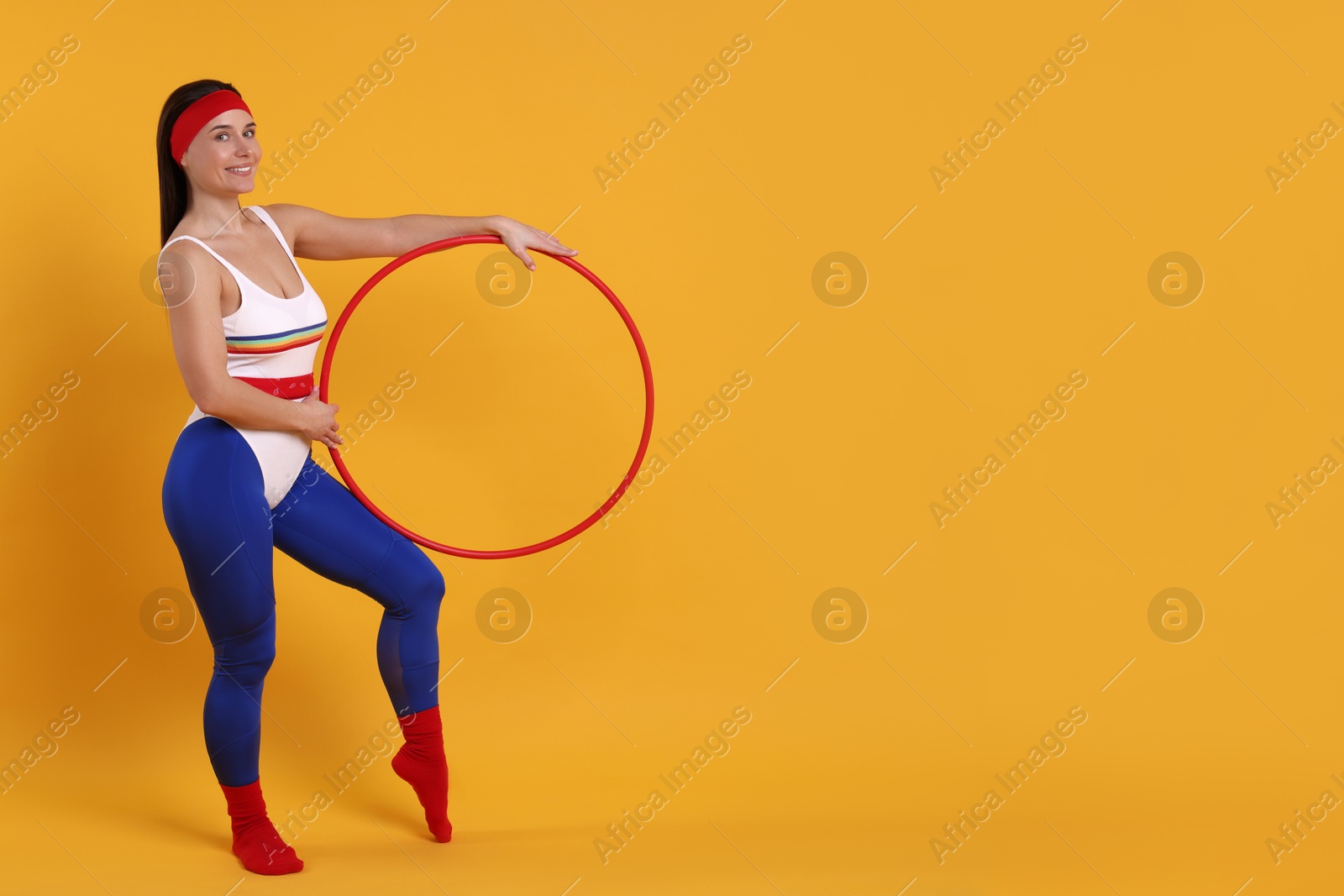 Photo of Smiling woman with hula hoop on orange background. Space for text