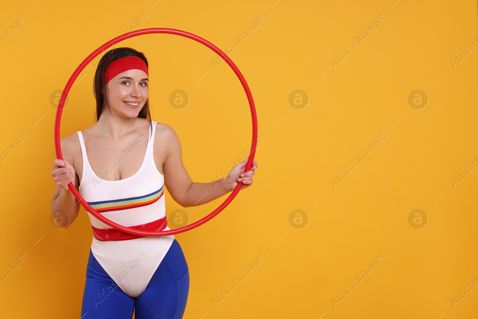 Photo of Smiling woman with hula hoop on orange background. Space for text