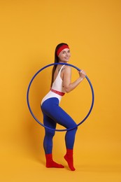 Photo of Smiling woman with hula hoop on orange background