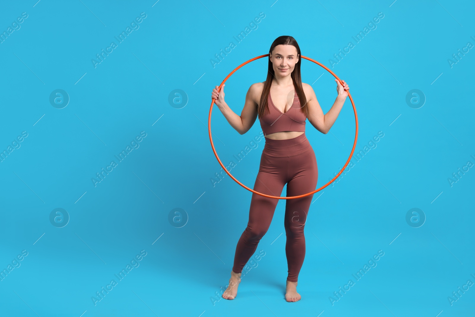 Photo of Beautiful woman with hula hoop on light blue background. Space for text