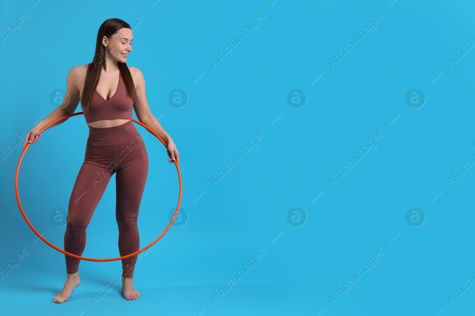 Photo of Smiling woman with hula hoop on light blue background. Space for text