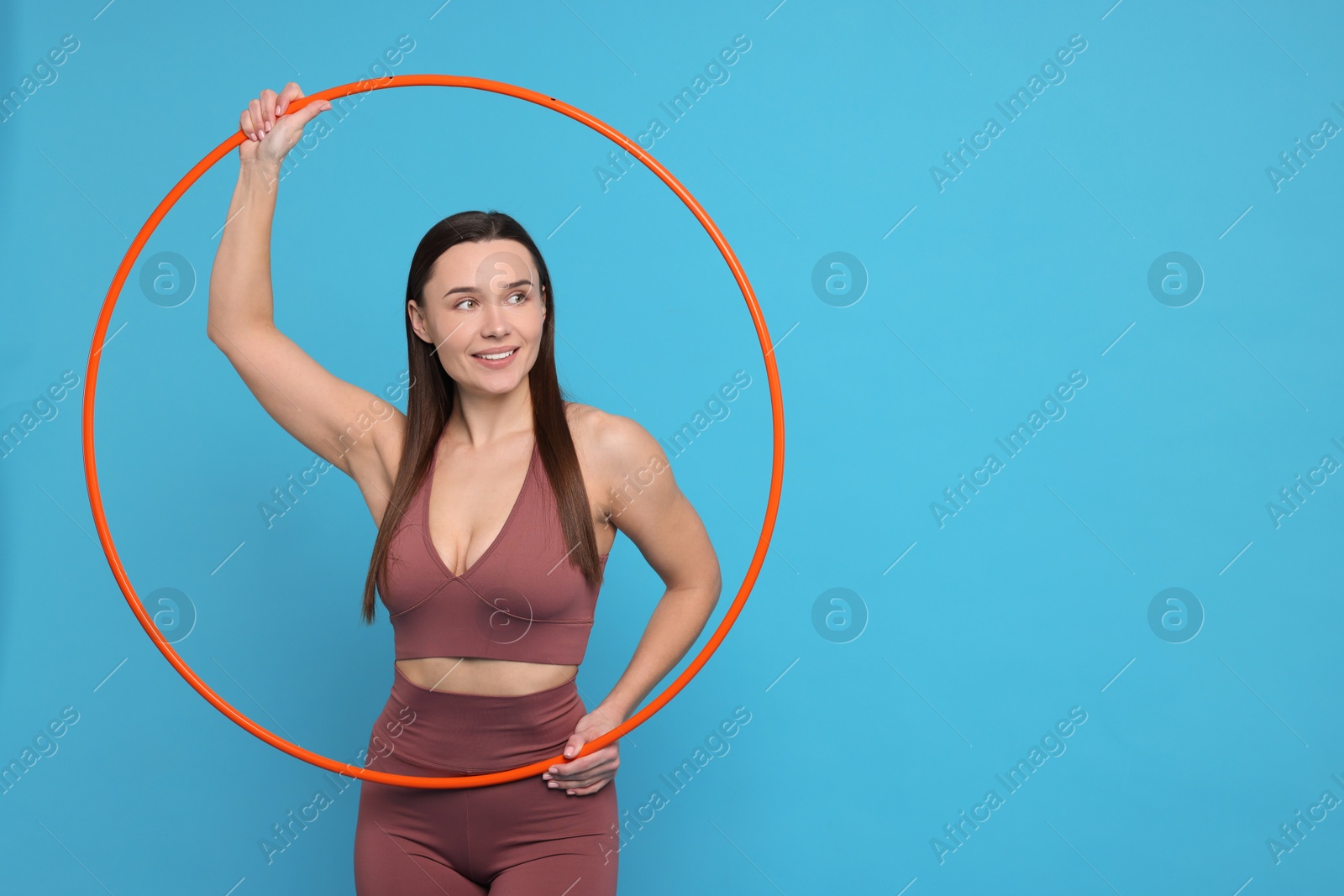 Photo of Smiling woman with hula hoop on light blue background. Space for text