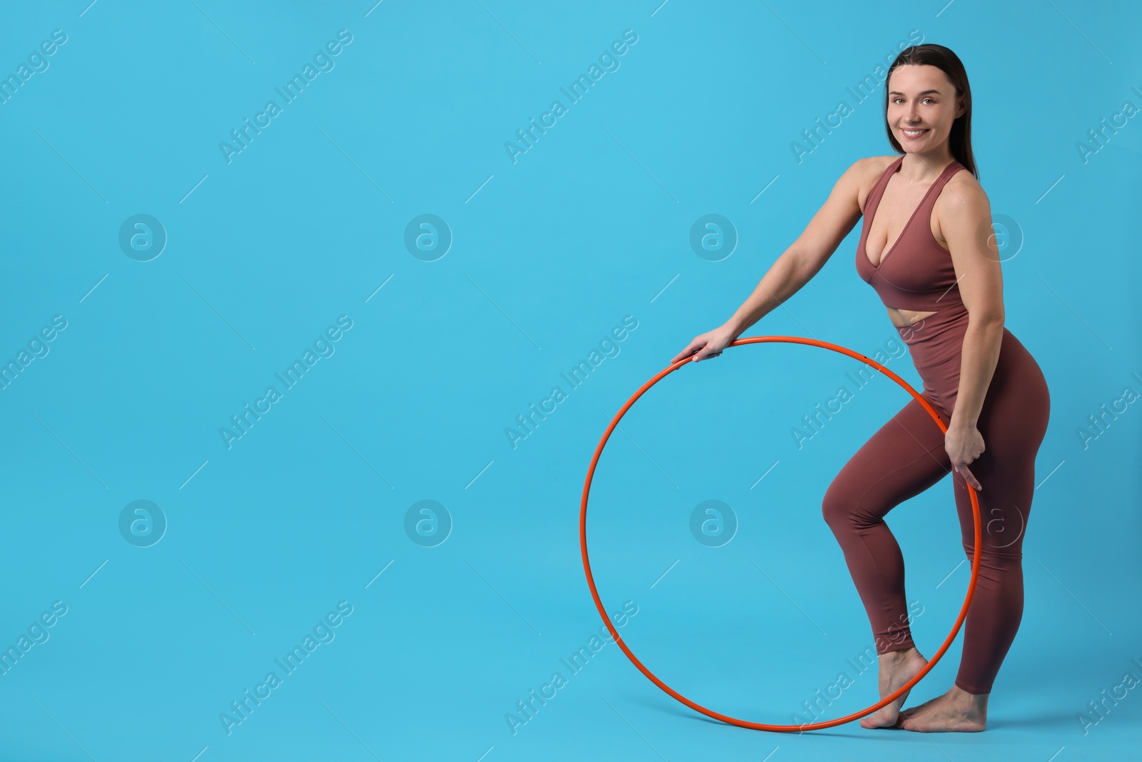 Photo of Smiling woman with hula hoop on light blue background. Space for text