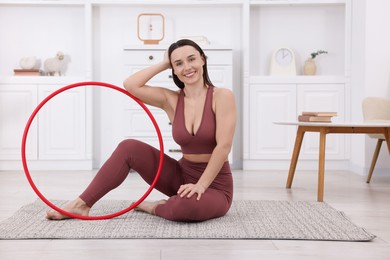 Smiling woman with hula hoop at home