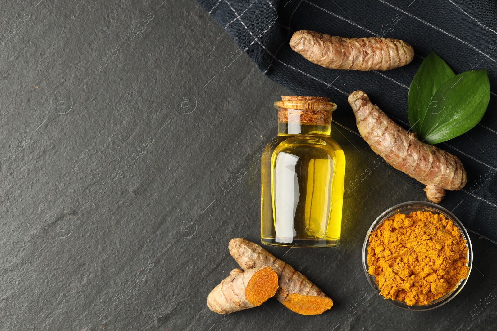 Photo of Tumeric oil, powder and roots on black table, flat lay. Space for text