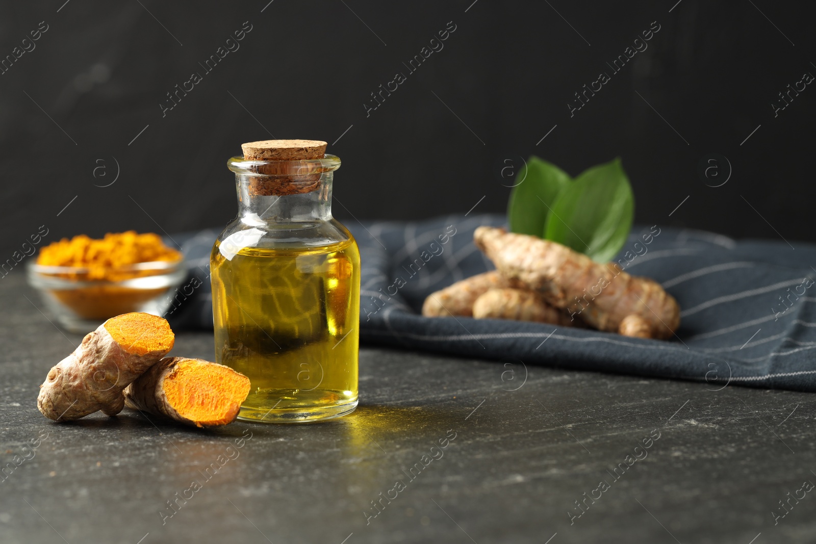 Photo of Tumeric oil and roots on black table, closeup