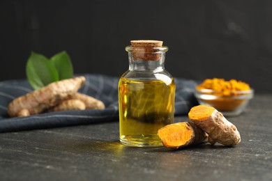 Photo of Tumeric oil and roots on black table, closeup