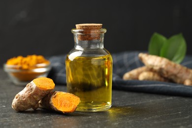 Photo of Tumeric oil and roots on black table, closeup