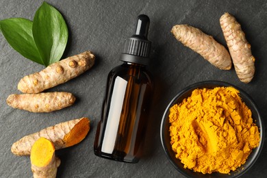 Photo of Tumeric oil, powder and roots on black table, flat lay