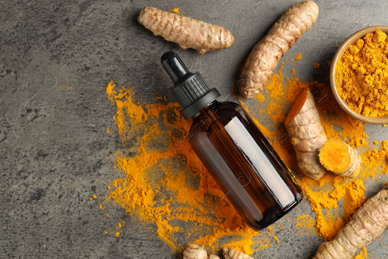 Photo of Tumeric oil, powder and roots on grey table, flat lay. Space for text