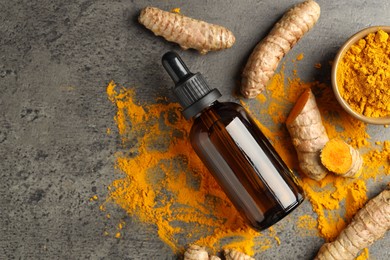 Photo of Tumeric oil, powder and roots on grey table, flat lay. Space for text