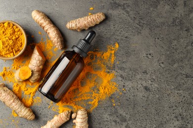 Photo of Tumeric oil, powder and roots on grey table, flat lay. Space for text