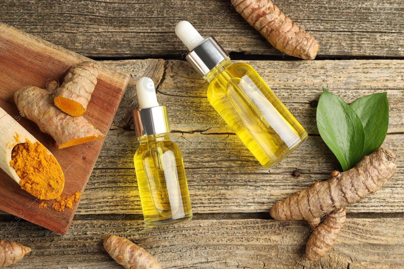 Photo of Tumeric oil, powder and roots on wooden table, flat lay