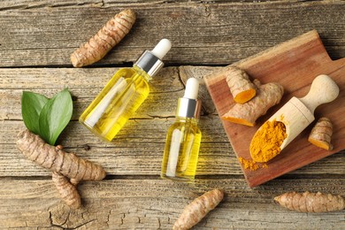 Photo of Tumeric oil, powder and roots on wooden table, flat lay