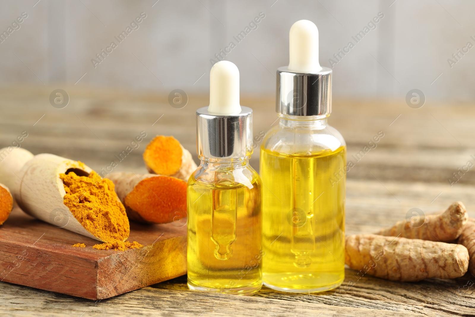 Photo of Tumeric oil, powder and roots on wooden table, closeup