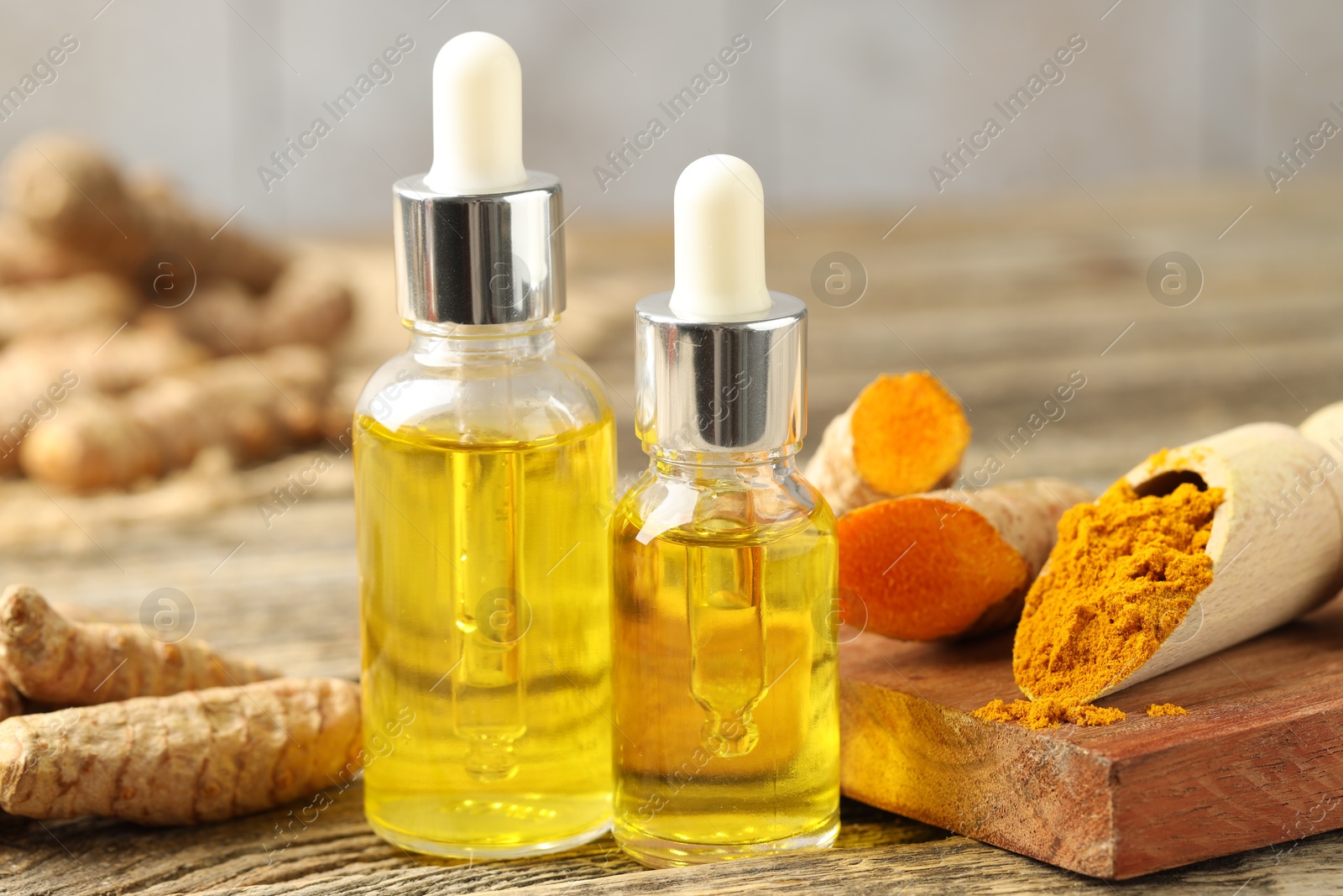 Photo of Tumeric oil, powder and roots on wooden table, closeup