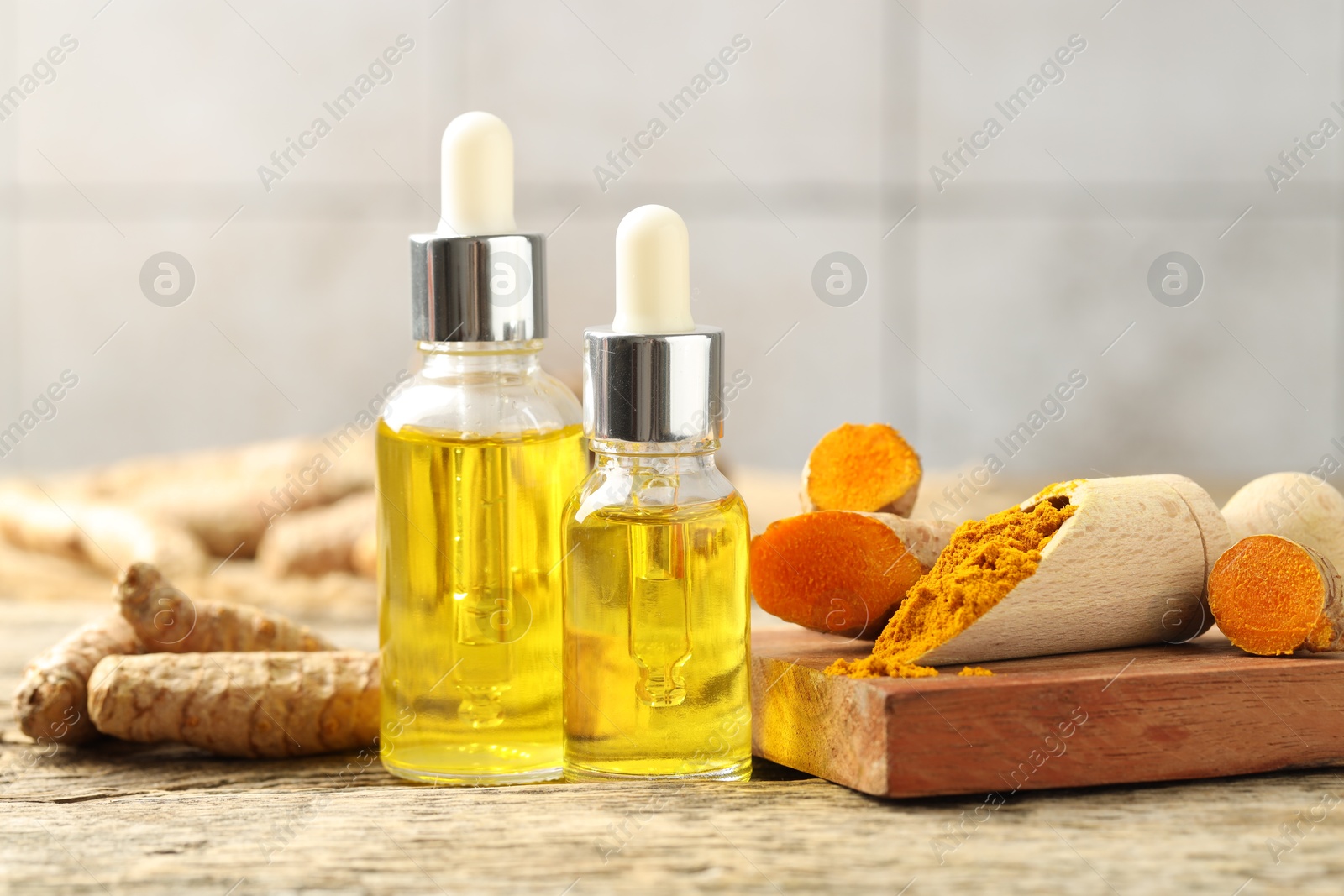 Photo of Tumeric oil, powder and roots on wooden table