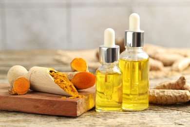 Photo of Tumeric oil, powder and roots on wooden table