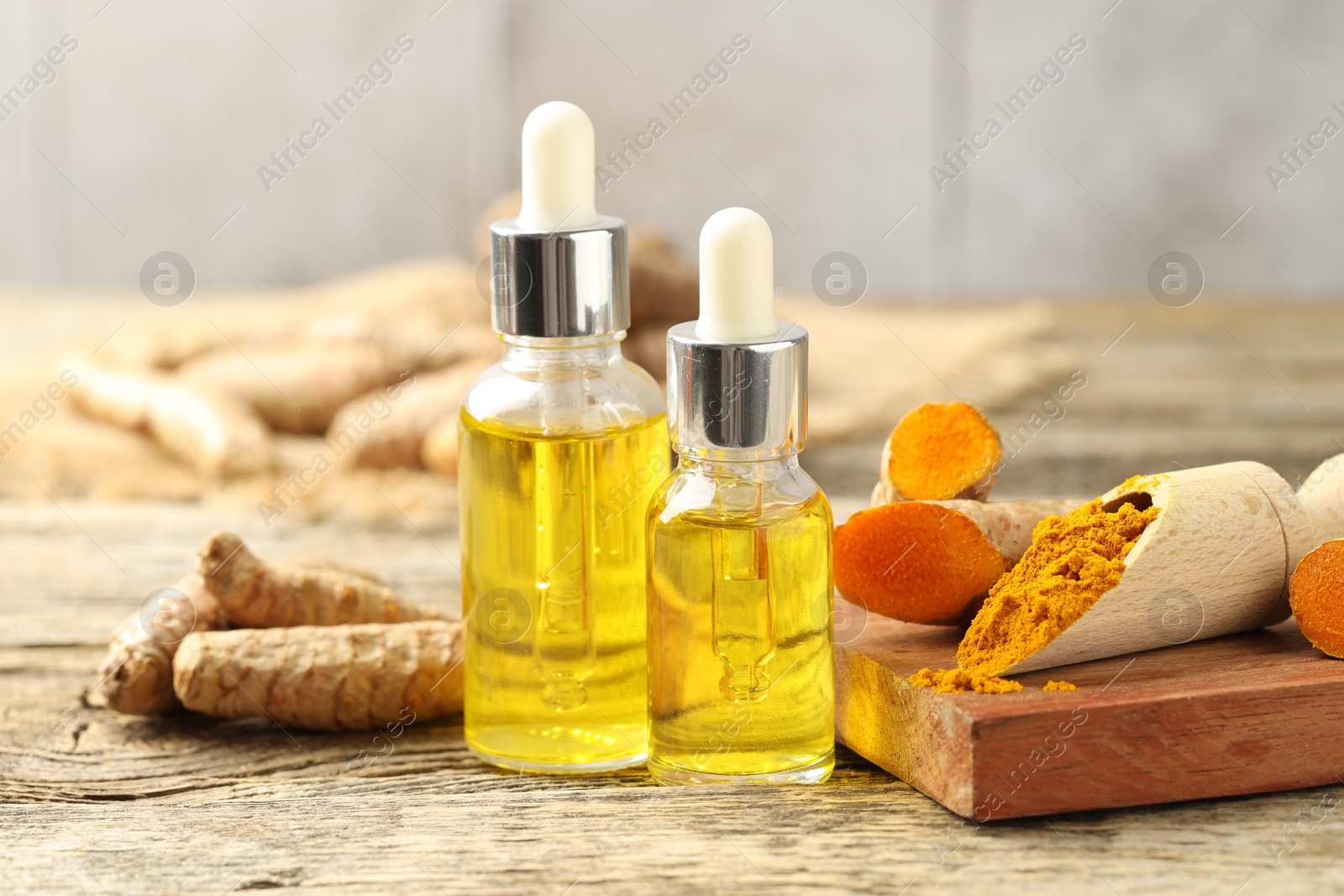 Photo of Tumeric oil, powder and roots on wooden table