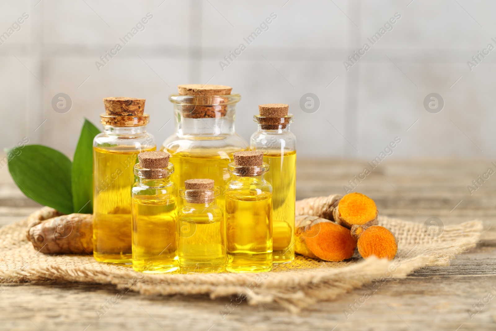 Photo of Tumeric oil and roots on wooden table, closeup