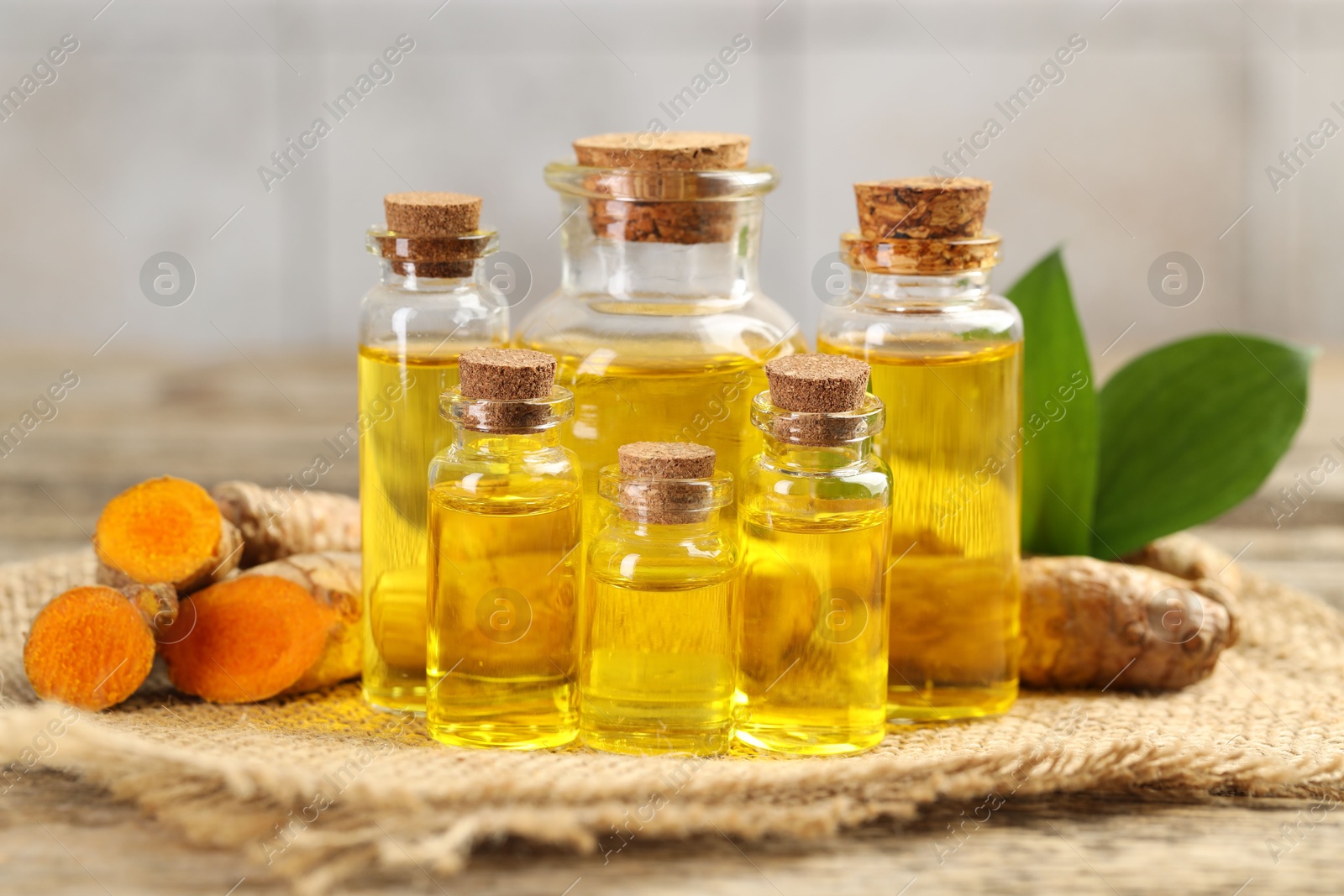 Photo of Tumeric oil and roots on wooden table, closeup