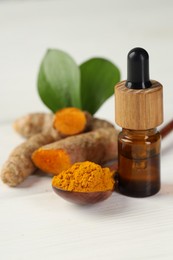 Photo of Tumeric oil, powder and roots on white table, closeup