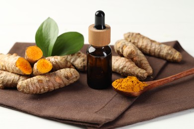 Photo of Tumeric oil, powder and roots on white table