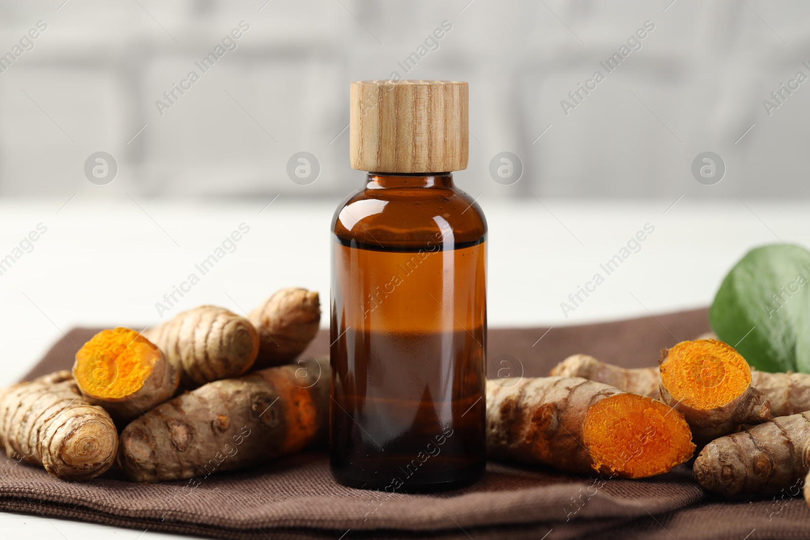 Photo of Tumeric oil and roots on white table, closeup