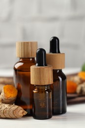 Photo of Tumeric oil and roots on white table, closeup