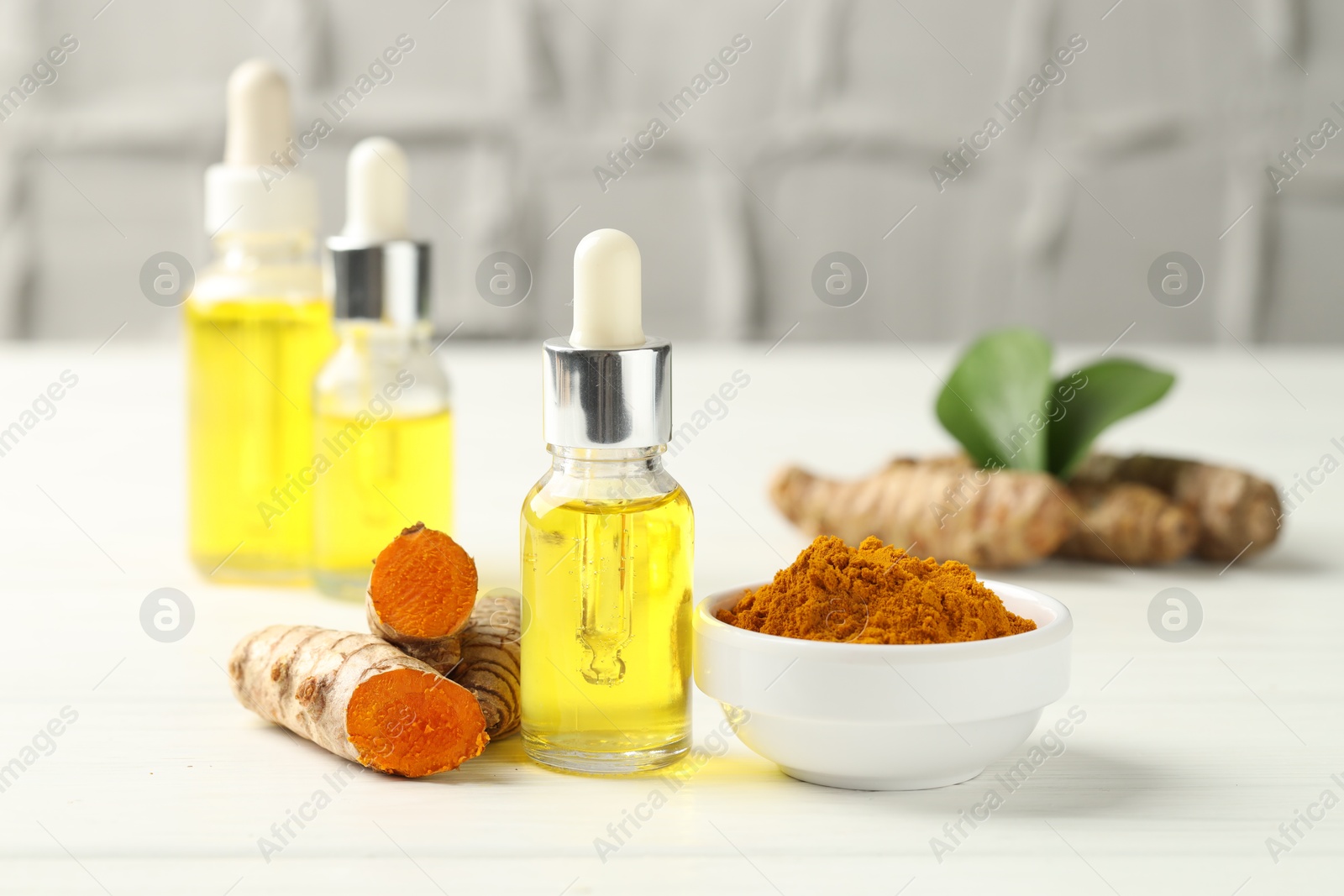 Photo of Tumeric oil, powder and roots on white table