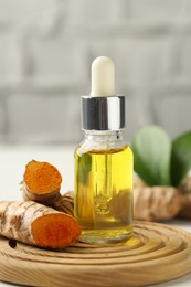 Photo of Tumeric oil and roots on white table, closeup