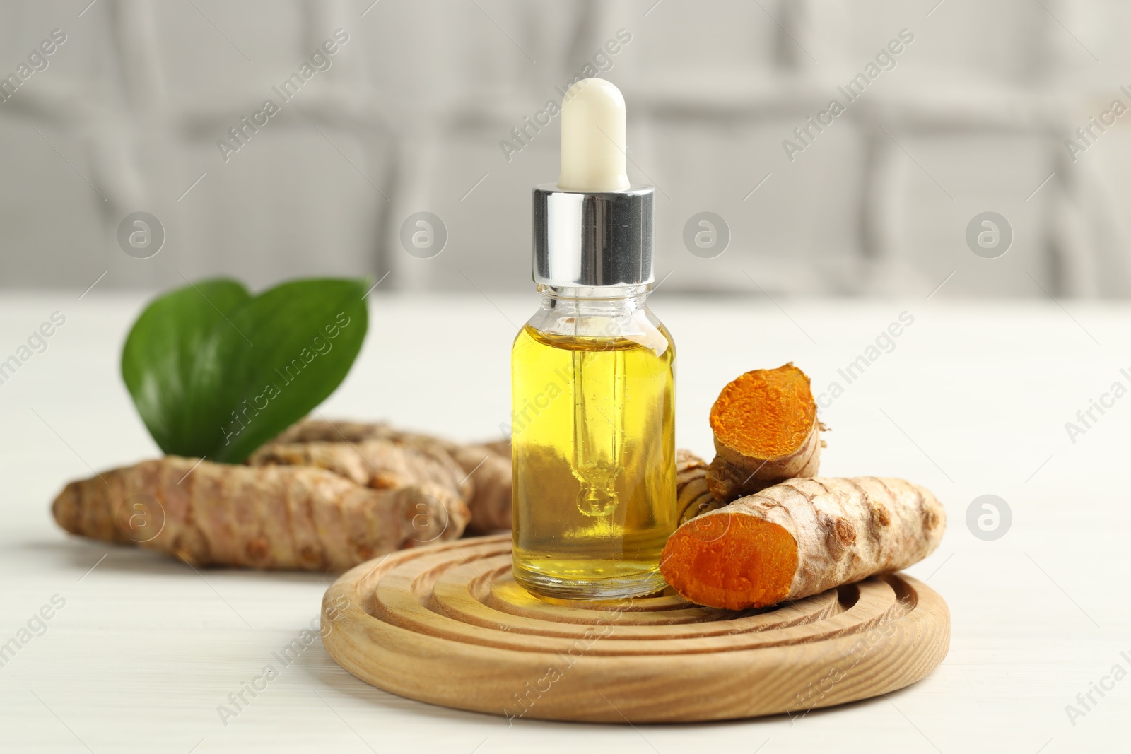 Photo of Tumeric oil and roots on white table, closeup