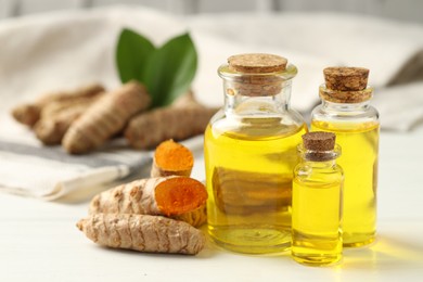 Photo of Tumeric oil and roots on white table, closeup