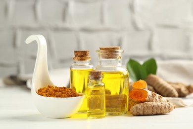 Photo of Tumeric oil, powder and roots on white table, closeup