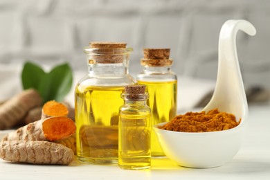 Photo of Tumeric oil, powder and roots on white table, closeup