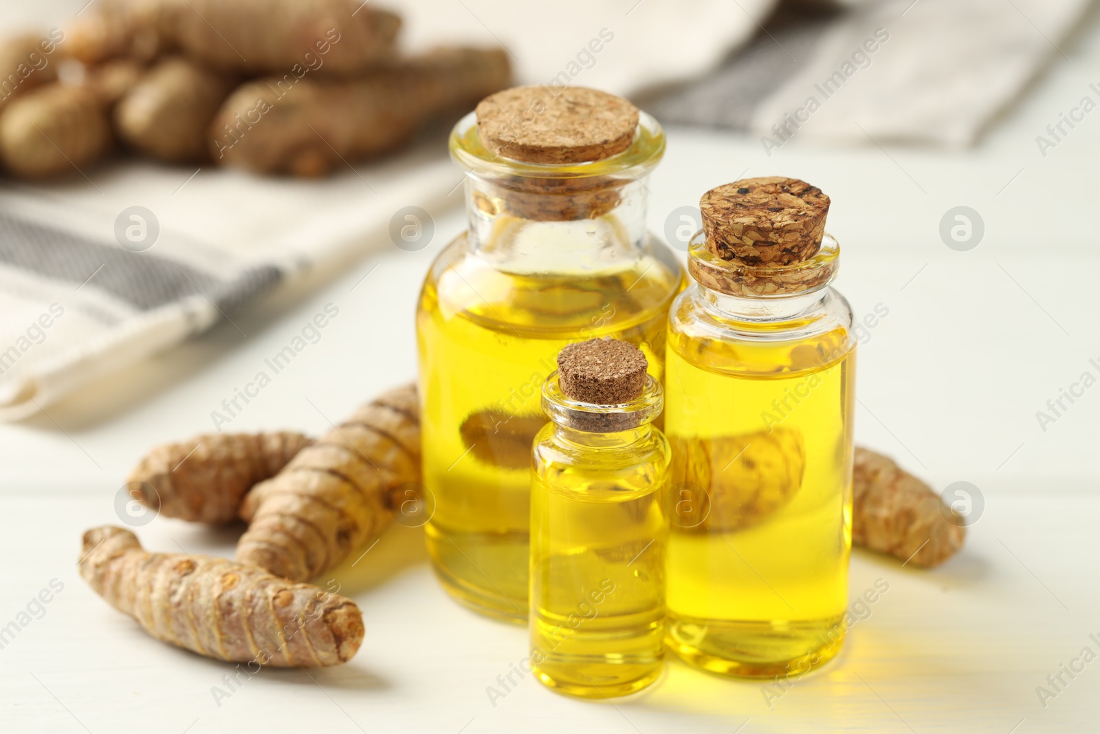 Photo of Tumeric oil and roots on white table, closeup