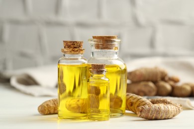 Photo of Tumeric oil and roots on white table, closeup