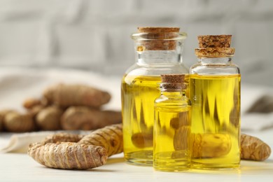 Photo of Tumeric oil and roots on white table, closeup