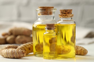 Photo of Tumeric oil and roots on white table, closeup